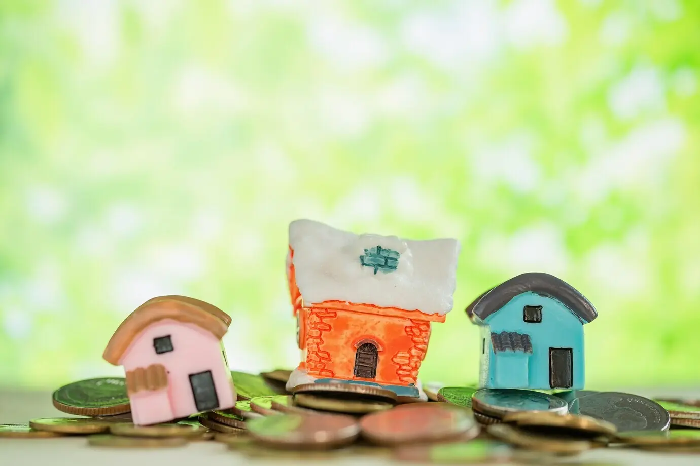 A small house atop a pile of coins with a green blur.